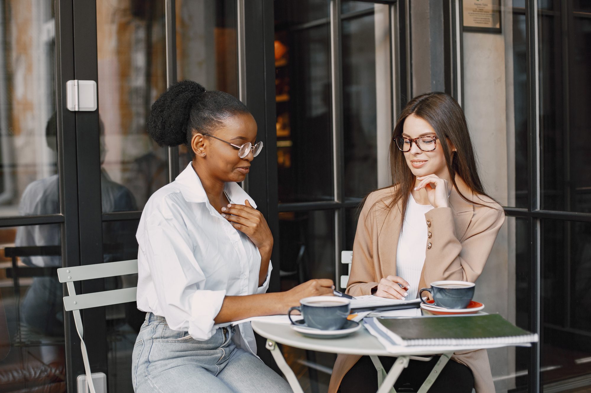 Deux professionnelles échangent en terrasse de café